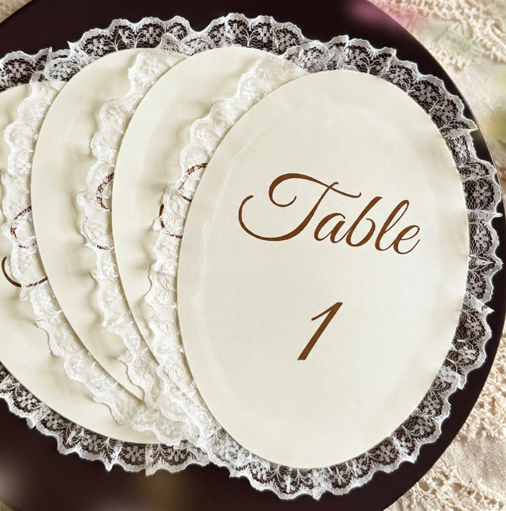 Stapel ovale tafelnummerkaarten met kantrand en het opschrift Table 1 in bruin schrift